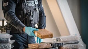Vancouver workers opened a shipping container of T-shirts and found 14 duffle bags holding 329kg of cocaine worth C$5.8 million; police say it is the city’s largest-ever cocaine seizure